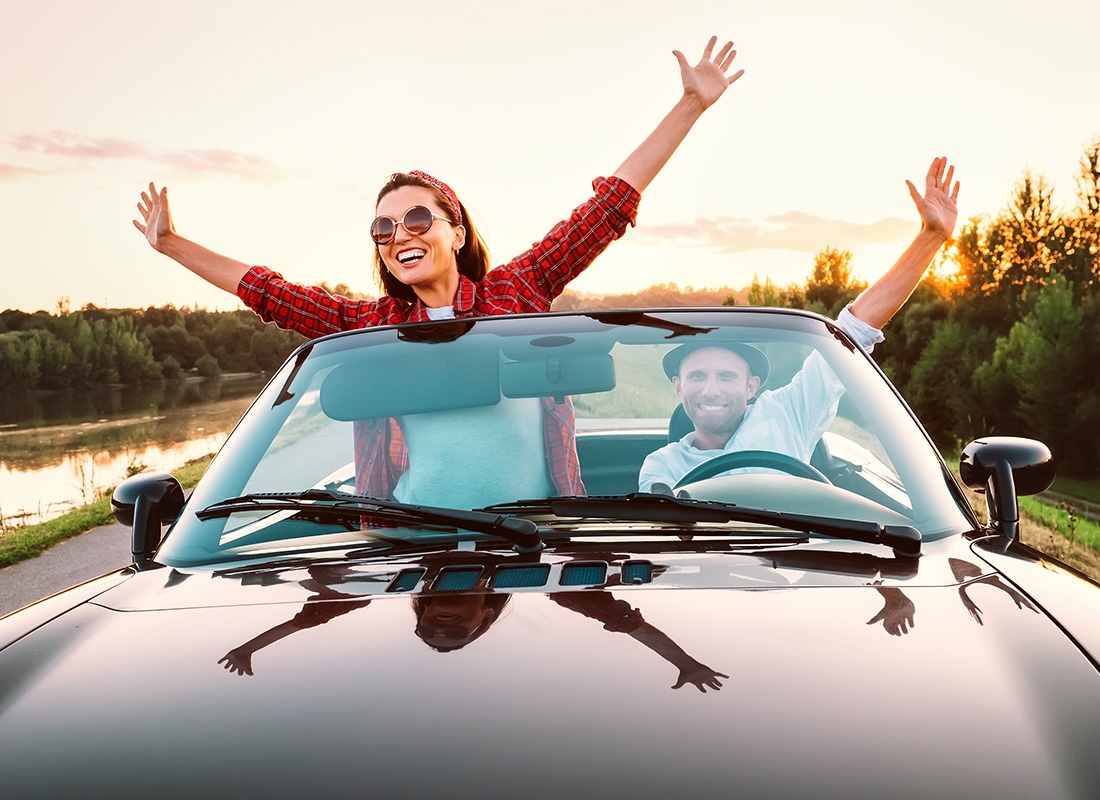 Insurance Solutions - View of a Cheerful Young Couple Having Fun Driving Through the Countryside in a Convertible at Sunset